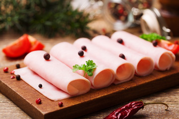 Delicious canned cooked ham on a wooden board with spices.
