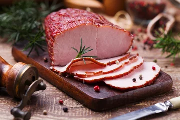 Fotobehang Delicious smoked ham on a wooden board with spices. © gkrphoto