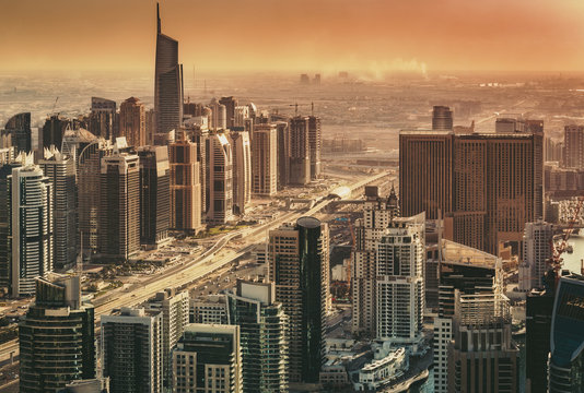 Scenic view of modern city architecture in dramatic sunset light. Aerial skyline of Dubai Marina, UAE, with skyscrapers. Architecture and travel background.
