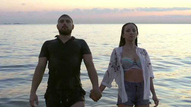 Man and woman fall into the lake slow-mo. Boy and girl immerse under water. Couple of people hold hand and go into the sea in slow motion. European guy and girlfriend relax in the evening slowmotion.