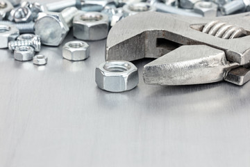 wrench and various screws for hand work on grey scratched metal