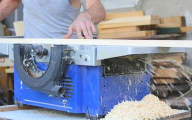 Man hand carpenter processing wooden beams on the machine