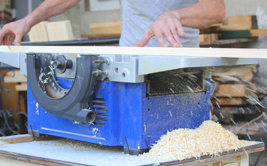 Man hand carpenter processing wooden beams on the machine