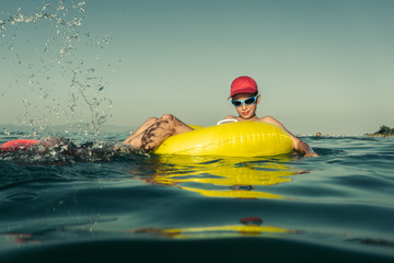 Funny child with diving mask and flippers enjoying summer on yellow inflatable smiling. Summer vacation concept. Vintage effect.