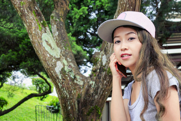 close up beautiful girl using mobile smart phone on desk in garden, over light [blur and select focus background]