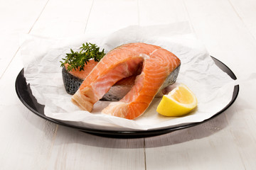 raw salmon steak with thyme and lemon on a plate