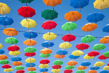 multicolored umbrellas row in blue sky