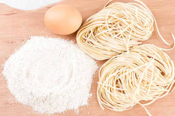 Ingredients for pasta and homemade pasta on wooden background