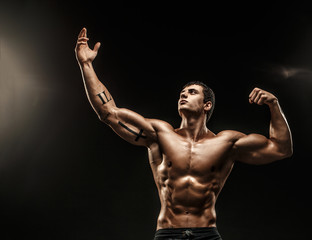 Handsome man with muscular topless body holding arms up. Isolated.
