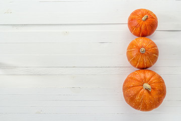 Background with three pumpkins on a white wooden boards. Space f