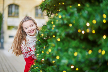 Young woman on a street of Paris decorated for Christmas