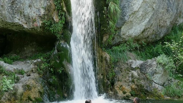 Two young people swimming in lake with waterfall, Olympus Greece, panning zoom out