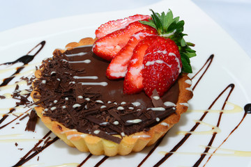 Bittersweet chocolate tartlet topped with sliced strawberry 