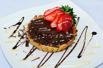 Bittersweet chocolate tartlet topped with sliced strawberry 