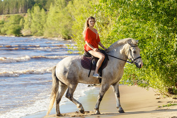 Young beautiful blonde woman ride her horse near the river