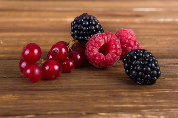 Wild berries: raspberries, blackberries, currants on a wooden background