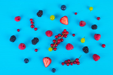 Various berries and fruits on a blue background. Top view .