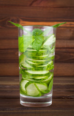 Refreshing cocktail of cucumber and mint leaves on a wooden background