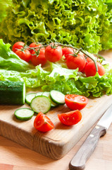 Ingredients for a vegetable salad on wooden cutting board