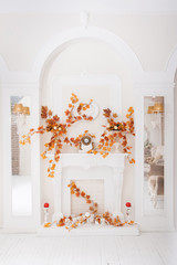 White classical fireplace in large hall with autumn decoration