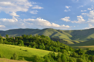 Landscape of Zlatibor Mountain. Green meadows and hills under blue sky with clouds in springtime