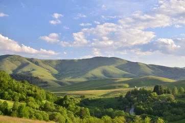 Zelfklevend Fotobehang Landschap van de berg Zlatibor. Groene weiden en heuvels onder blauwe lucht met wat wolken in de lente © branislav