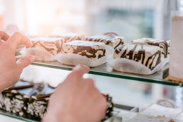 Waitress arranging cake at display cabinet