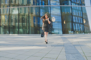 beautiful girl in black with a bag in hand on the background of the business center