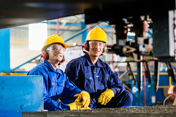 Worker in factory at industrial metal cutting machine