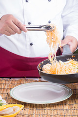 Chef fork over noodles by tongs