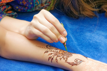 young woman mehendi artist painting henna on the hand