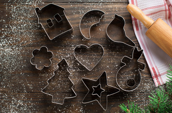 Christmas background with cookies cutters, flour, spices and green fir branches on old rustic wooden table, top view