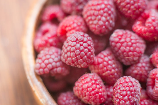 Macro photo of raspberry in wooden bowl, fresh berries close up, summer background