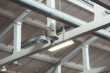 Industrial interior details: ceiling beams and pipes on factory, loft styled vintage lamps