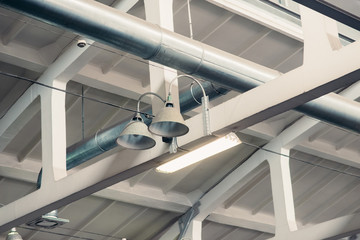 Obraz premium Industrial interior details: ceiling beams and pipes on factory, loft styled vintage lamps