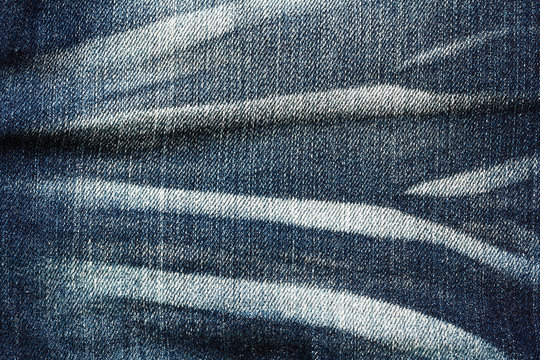texture of dark blue denim with pleats and scuffed as a backgrou
