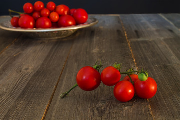 branch of small red ripe tomato closeup on wooden background