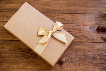 Gift box with gold bow on wood background