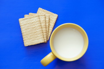 
Cup with milk and crackers are isolated on a colored background
