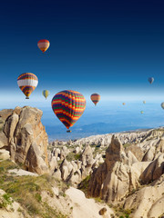 Heteluchtballonnen vliegen in een heldere, diepblauwe lucht in Cappadocië