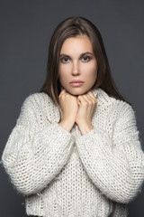 Beautiful blond young girl wear winter pullover over gray background