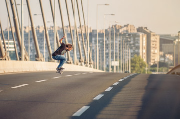 Skateboarder riding a skate and doing jumps on the city road bri