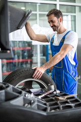 mechanic repairman installing car wheel on tyre