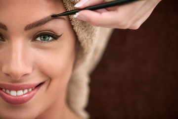 Smiling beautiful woman on professional make up treatment