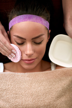 beautician cleaning face of young female