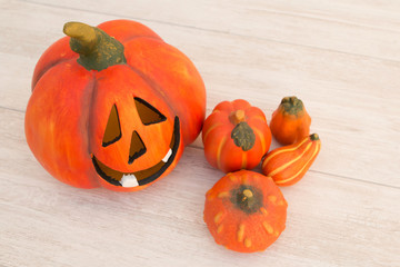 Orange pumpkin lantern with a spooky face smiling on a wooden gr
