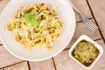 Tagliatelle with pesto decorated with basil on a wooden background