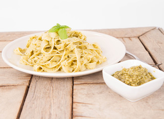 Tagliatelle with pesto decorated with basil on a wooden background