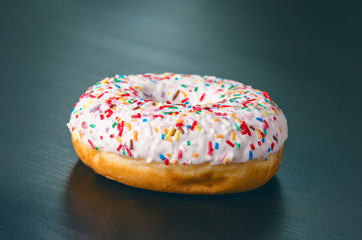 Donut with sprinkles and white iced. Donuts background. Cake and sweet. Food
