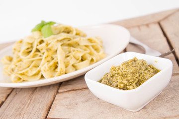 Tagliatelle with pesto decorated with basil on a wooden background